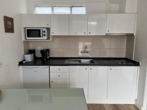 a white kitchen with a sink and a microwave at Sintra Sol - Apartamentos Turisticos in Sintra