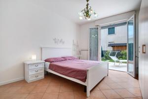 a white bedroom with a bed and a window at Villetta Bruna in Lido di Jesolo