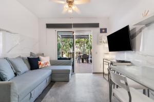 Una sala de estar con un sofá y un televisor. en Home2Book Relaxing Stay & Terrace in Maspalomas, en Maspalomas