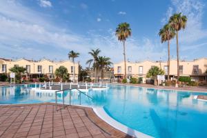 a large swimming pool with palm trees and buildings at Home2Book Relaxing Stay & Terrace in Maspalomas in Maspalomas