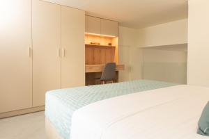 a bedroom with a white bed and a chair at Ikaros City Loft in Chania Town