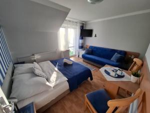 a living room with a bed and a blue couch at Willa Morski Klimat in Łeba
