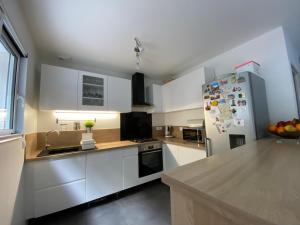a kitchen with white cabinets and a refrigerator at Maison familiale proche de paris in Bagneux