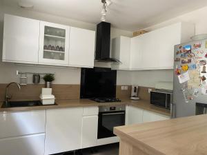 a kitchen with white cabinets and a stainless steel refrigerator at Maison familiale proche de paris in Bagneux +7 photos
