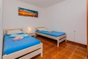 two beds in a room with blue sheets and pink towels at Apartments Juracak Josip i Mira in Grbe