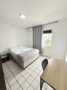a bedroom with a bed and a table and a window at APARTAMENTO NO MELHOR DE BOA VIAGEM in Recife