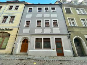 a gray building with brown doors on a street at Gassentraum NEU mit Balkon in Pirna
