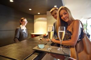 a woman holding a tray with two glasses of champagne at PortoBay Rio de Janeiro in Rio de Janeiro