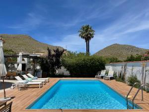a swimming pool with chaises and chairs next to a house at Villa Can Llompart Port de Pollensa in El Port