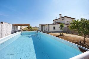 a blue swimming pool with a house in the background at Villa Manoli in Chiclana de la Frontera