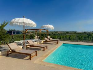a swimming pool with chairs and umbrellas next to a swimming pool at Dimora Calauriia - Adults Only in Noto