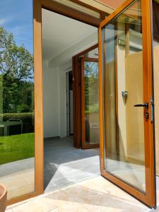 an open glass door of a house with a patio at Gîte 829 Montagnes du Jura avec Spa et Sauna classé 3 étoiles in Foncine-le-Haut