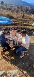 a group of people sitting at a picnic table at The Love Story Homestay in Bhatwāri