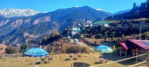 a group of chairs and umbrellas on a mountain at The Love Story Homestay in Bhatwāri