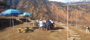 a group of people sitting at tables under umbrellas at The Love Story Homestay in Bhatwāri