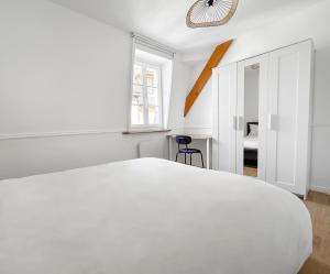 a white bedroom with a white bed and a window at Calme et confort au cœur du vieux Troyes in Troyes