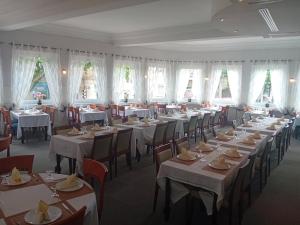 a dining room with tables and chairs and windows at Les nouveaux Ambassadeurs in Saint-Chamond