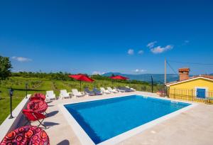 Una piscina con sillas y sombrillas al lado de una casa. en Villa Maslina, a charming and private villa 15 km from the sea, en Pićan