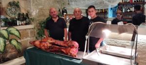 three men standing next to a table with a roast turkey at Ta' Gingel Farm Agriturisim B&B. Malta in St Paul's Bay