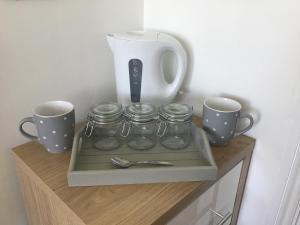 a shelf with jars and cups and a vase on it at The Annexe in Isle of Wight