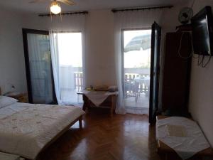 a bedroom with a bed and a television and a balcony at Villa Milas - Soba 02 in Tkon