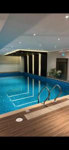 a large swimming pool with blue water in a building at Cozy one bed in Gulberg in Lahore