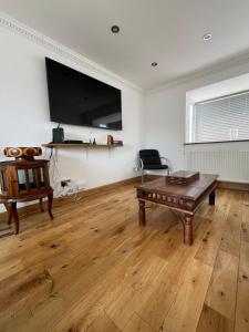 a living room with a table and a flat screen tv at Bungalow with hot tub & Sauna in Kingsgate