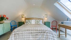 a bedroom with a bed with two chairs and a sink at Bwthyn Ysgubor in Conwy