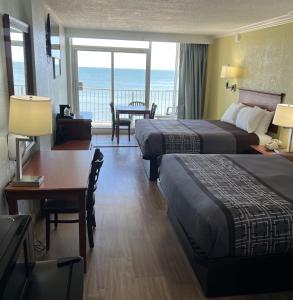 a hotel room with two beds and a desk with a table at Seahawk Motel in Virginia Beach