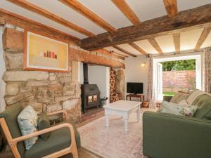 a living room with a fireplace and a stone wall at Old Farm Cottage in Warminster