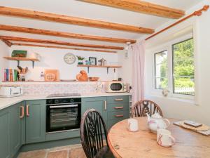 a kitchen with green cabinets and a wooden table at Old Farm Cottage in Warminster