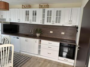 a kitchen with white cabinets and a black appliance at студия ЛИЛИЯ in Tsarevo