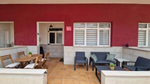 un patio avec des chaises et des tables et un mur rouge dans l'établissement Maravillosa by "BahiaMarCanarias", à La Estrella