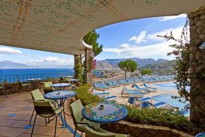un patio con tavoli, sedie e vista sulla spiaggia di Grand Hotel President a Sorrento