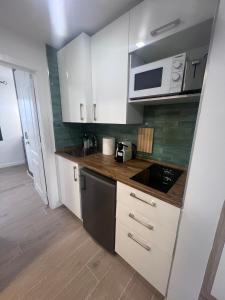 a small kitchen with white cabinets and a microwave at Can Paquito Fuerteventura in Corralejo