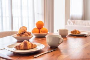 a table with plates of croissants and oranges on it at Moderno Apartamento in Marbella