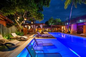 a swimming pool with chaise lounges and chairs around it at Pousada Quarto Crescente in Trancoso
