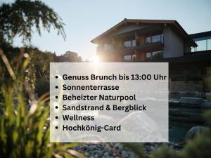 a sign in front of a house with a building at Wellness und Brunch Hotel MorgenZeit beheizter Naturpool mit Sandstrand Genuss Frühstück bis 13 Uhr Hochkönig Sommercard in Maria Alm am Steinernen Meer