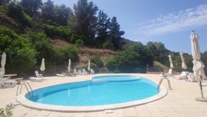 a large swimming pool with chairs and umbrellas at Appartamento Mare e Natura in Castelsardo