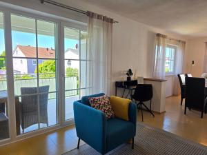 a living room with a blue chair and a balcony at Ferienwohnung Ingolstadt Eichstätt Altmühltal in Eitensheim