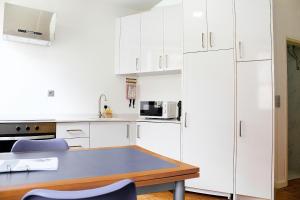 a kitchen with white cabinets and a blue table at São Pedro City Flat in Vila Real +18 photos