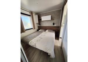 Un dormitorio pequeño con una cama y una ventana. en Mobil-home Clim, TV, LV Camping LES OYATS 4 étoiles - MH-A017, en Seignosse