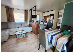 pequeña sala de estar con sofá y cocina en Mobil-home Clim, TV, LV Camping LES OYATS 4 étoiles - MH-A017, en Seignosse