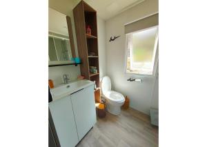 Un baño con un lavabo blanco y un inodoro. en Mobil-home Clim, TV, LV Camping LES OYATS 4 étoiles - MH-A017, en Seignosse 5 fotos más