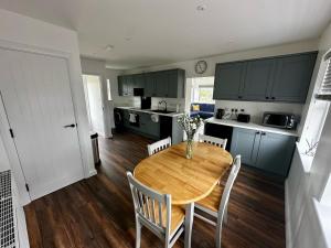 a kitchen with a wooden table and chairs in a room at Kennedy Farm Lodge in Carmavy