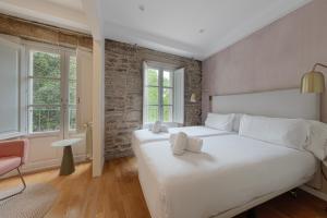 Un dormitorio con una gran cama blanca y dos ventanas. en Catedral Site by Como en Casa, en Santiago de Compostela
