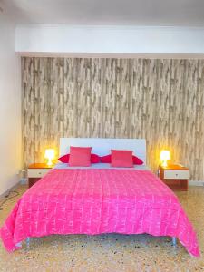 a pink bed with two red pillows in a bedroom at Casa Linda in Lido di Ostia
