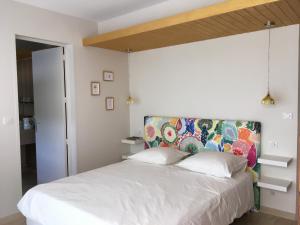a bedroom with a white bed with a colorful headboard at La Villa des Poètes in Nyons +21 photos