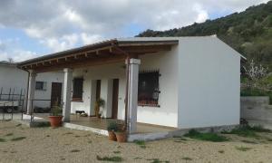 a white house with a porch and a balcony at Agriturismo Locoe in Oliena