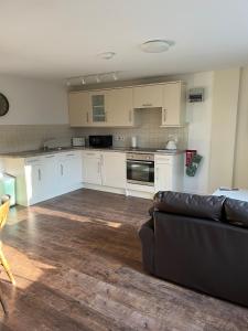 ein Wohnzimmer mit Couch und Küche in der Unterkunft Hanley Swan, The Garden Flat in Madresfield